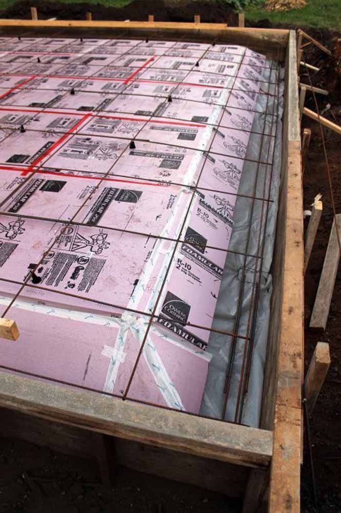 Foundation construction with pink foam insulation, rebar grid, and wooden framing.