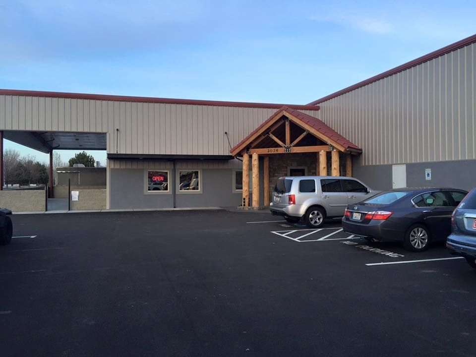 Exterior of a building with a rustic wood entrance and cars parked in front.
