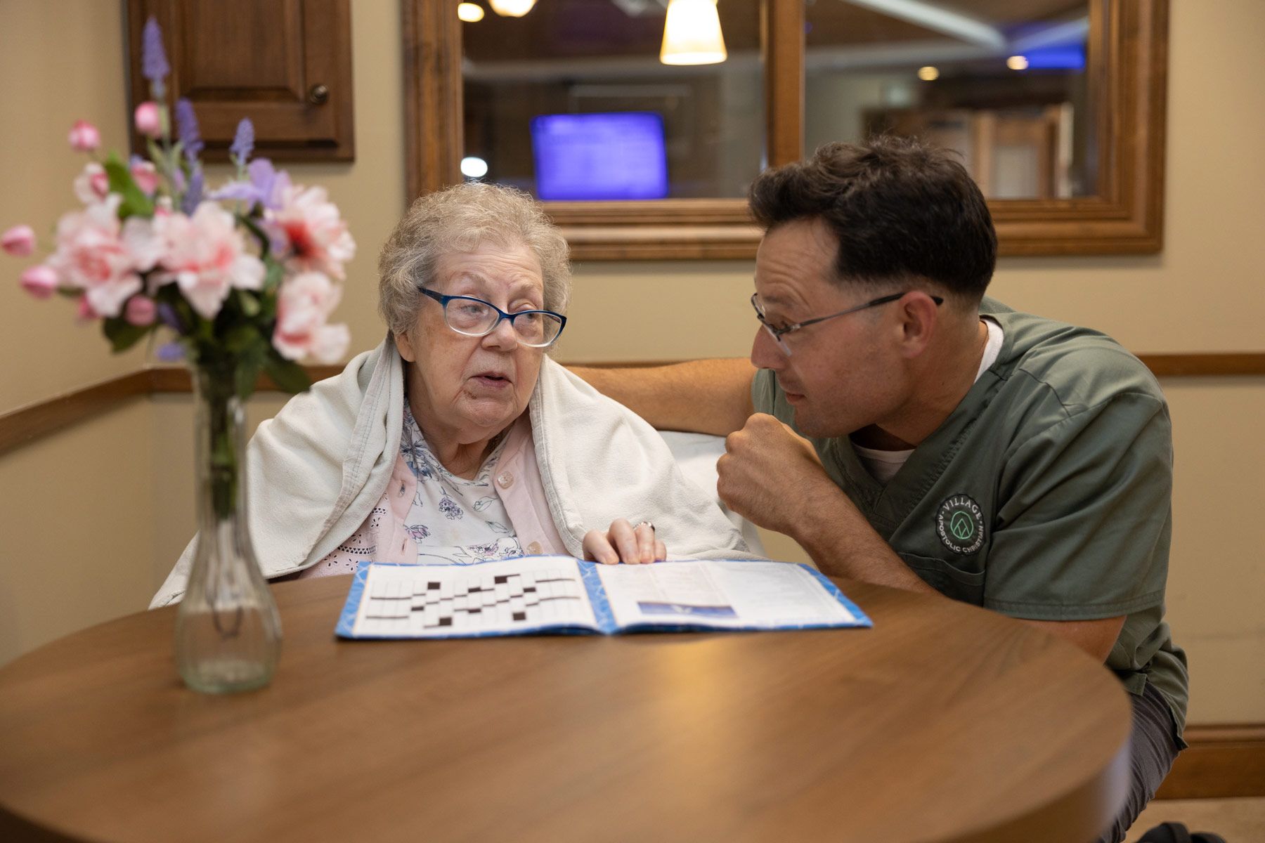 Senior woman and caregiver looking at a document at a table indoors.