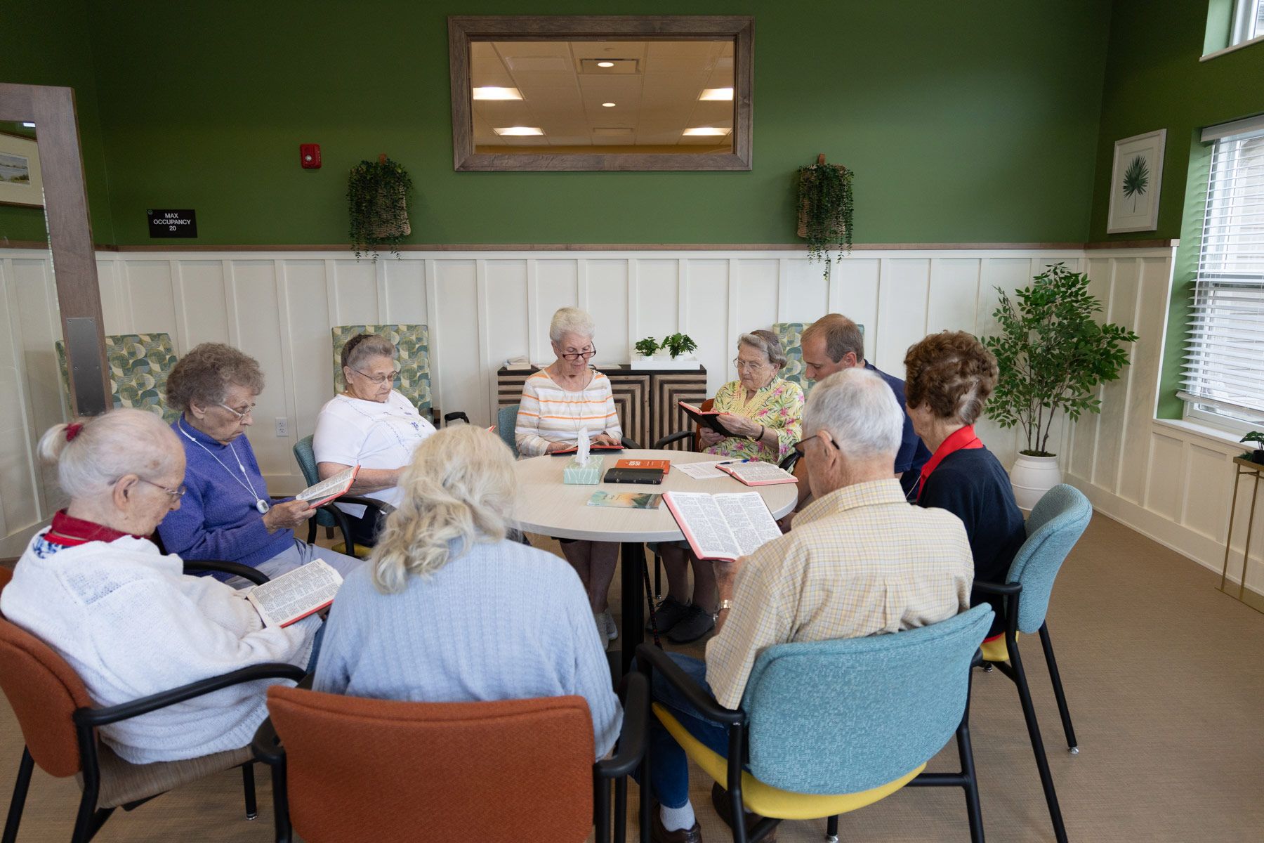 A group of people sitting around a table in a room with green walls, playing a game.