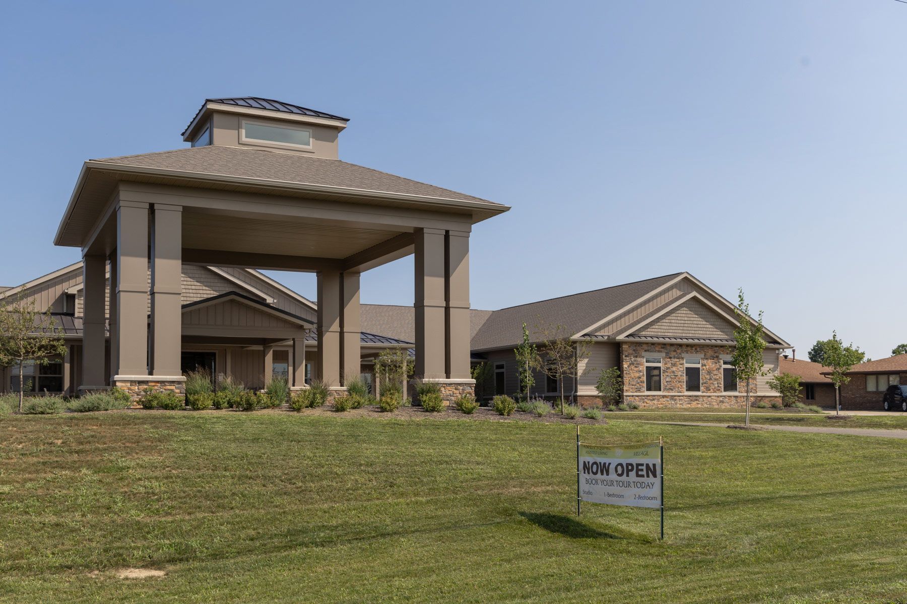 A beige, two-story building with a covered entryway and a