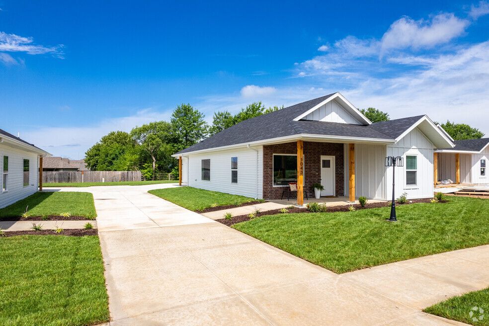 a white house with a black roof is sitting on top of a lush green lawn .