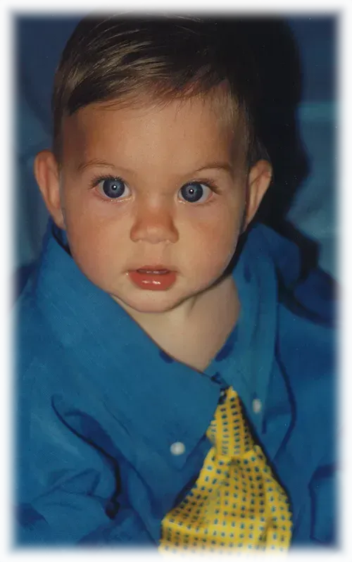 A baby wearing a blue shirt and a yellow tie.