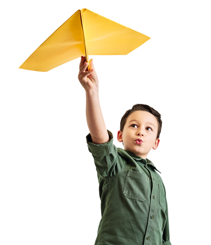 A young boy in a green shirt is holding up a yellow paper airplane.