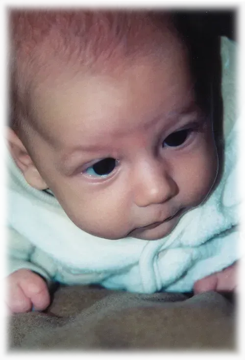 A baby is laying down and looking at the camera.