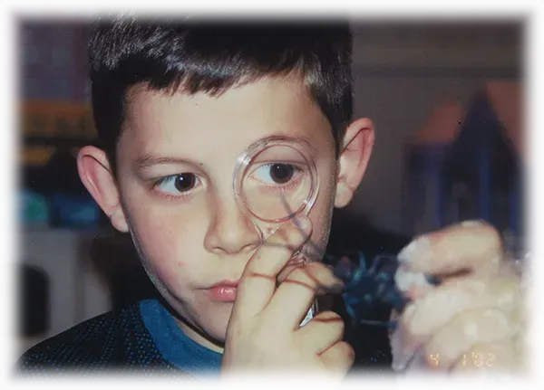 A young boy is looking through a magnifying glass.