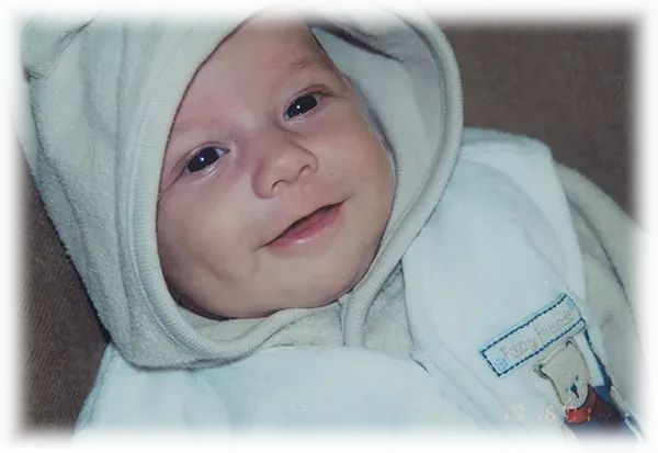 A baby wearing a white hooded jacket with a bear on it.