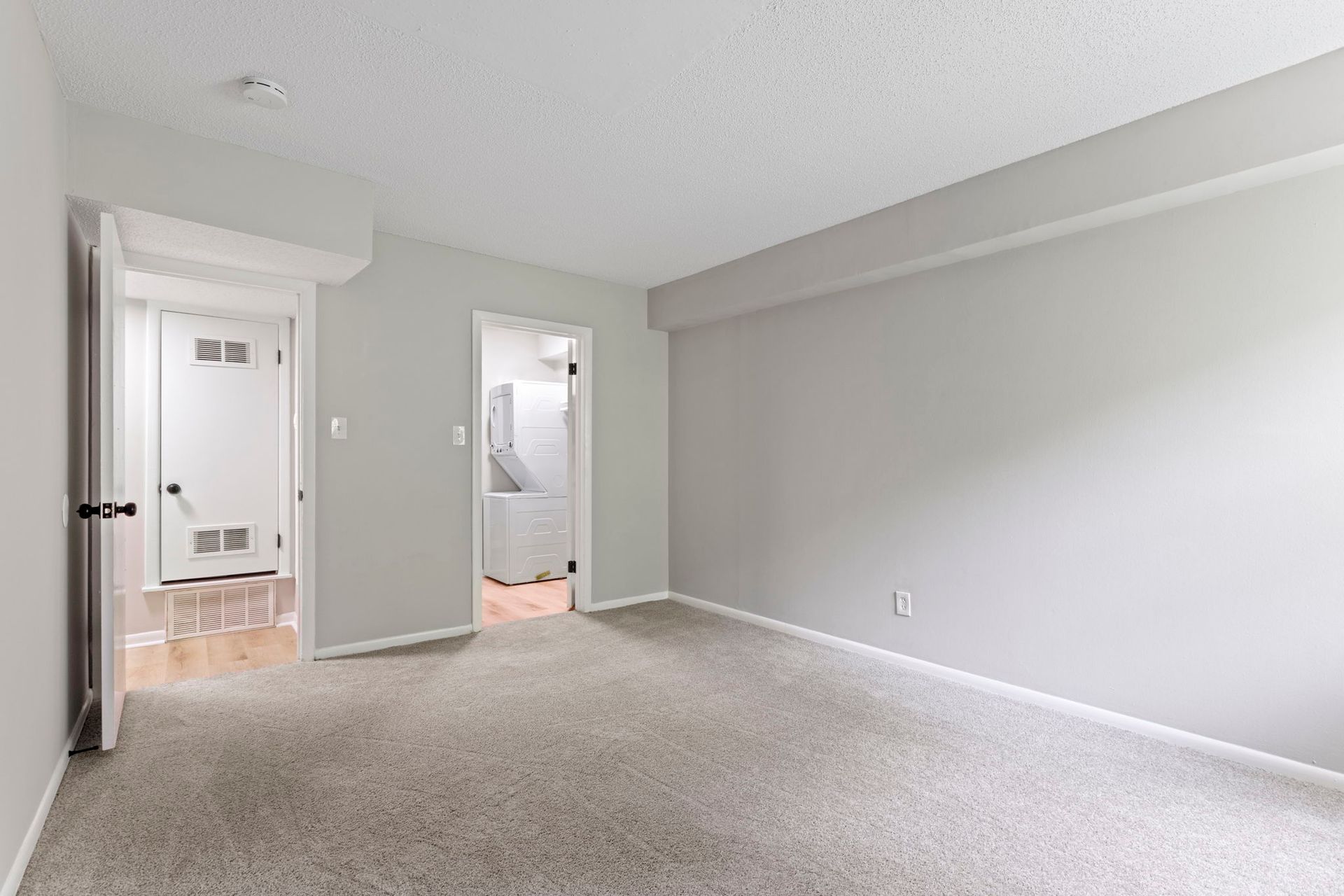 Empty bedroom with gray walls, carpet, and two doorways.