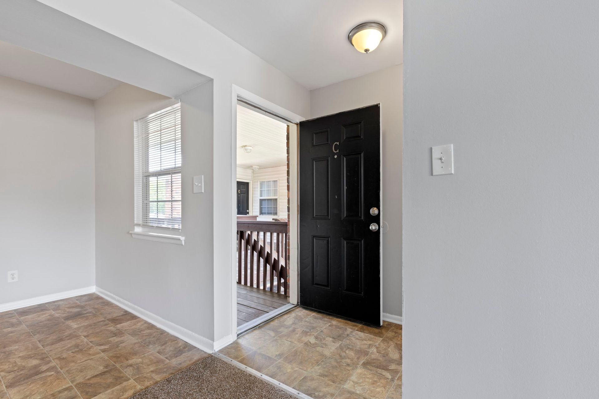 Entryway with a black door, light gray walls, and linoleum flooring.
