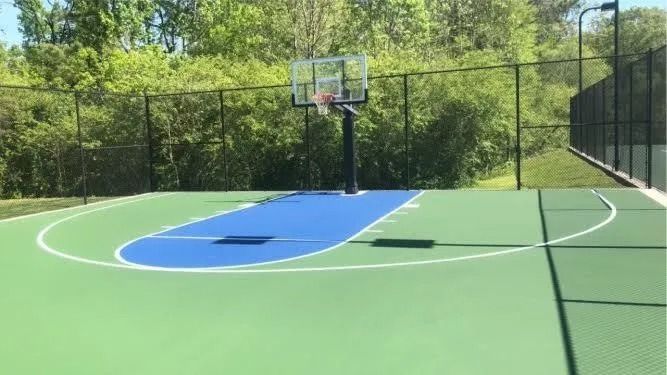 A Tennis Court With a Net and a Basketball Hoop in the Background