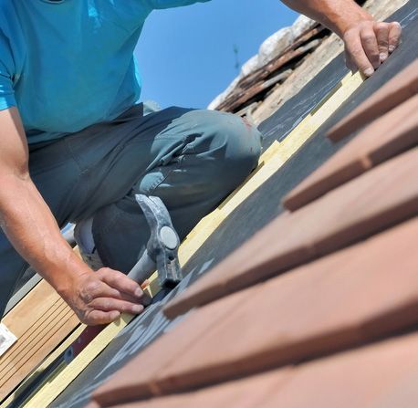 Close on a worker holding a hammer and renoving a roof of a house