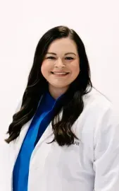 Smiling professional in a white coat and blue shirt against a light background