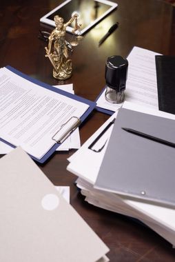 Desk with papers, folders, a pen, and a small gold statuette on a dark table.