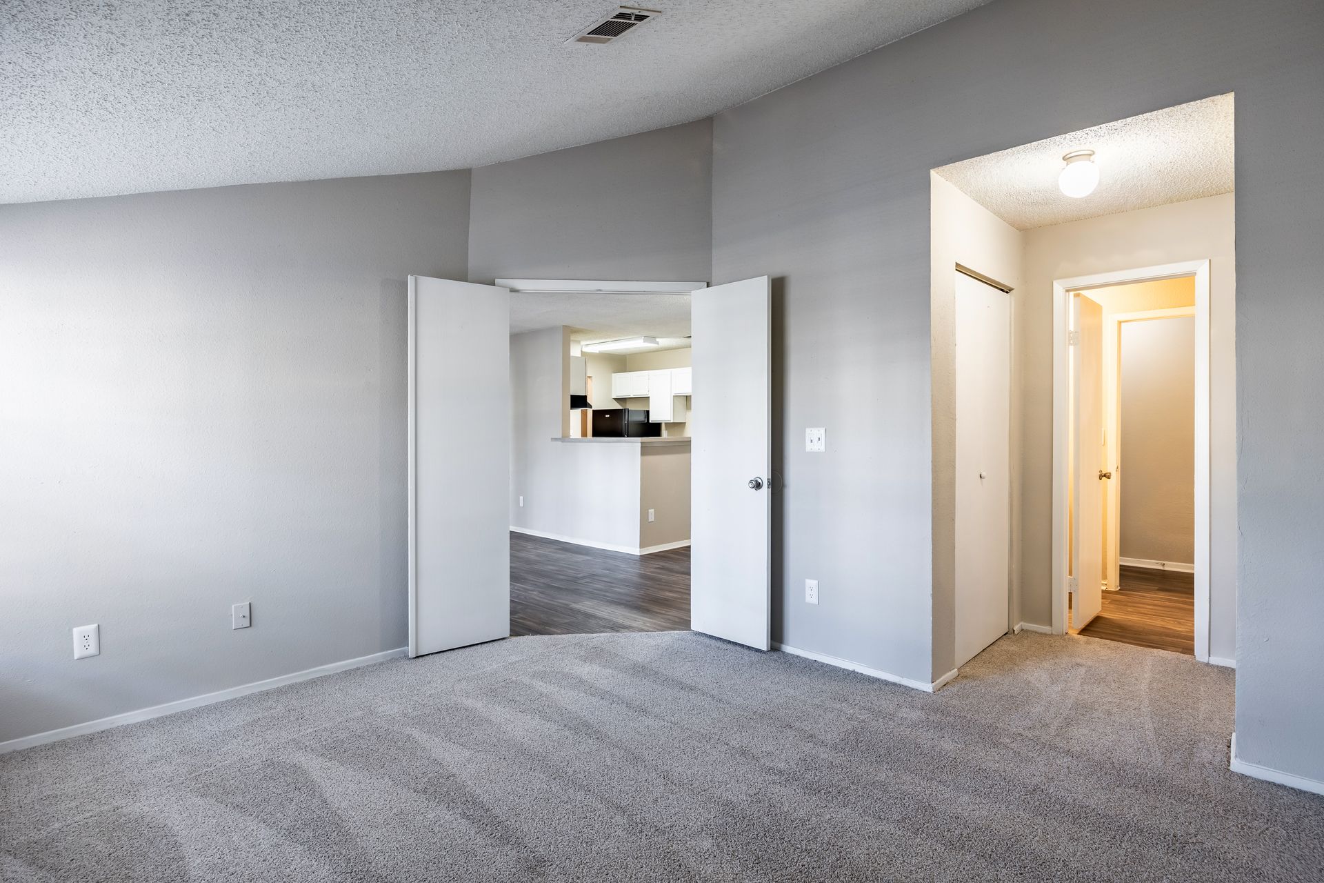 Dining area with glass table, chairs, artwork, and view into kitchen and living room.