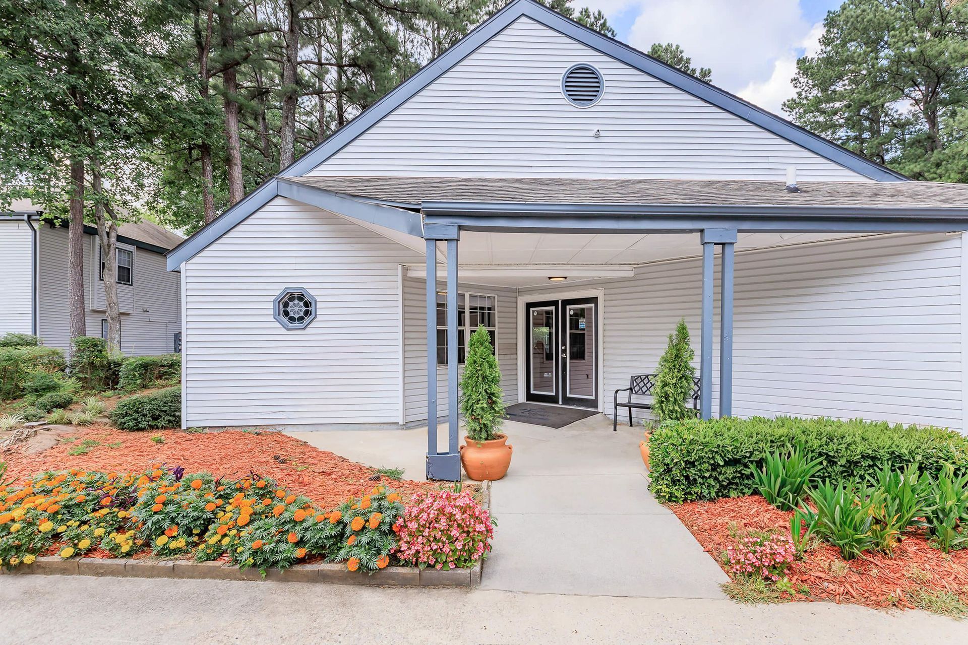 Brick building with white columns, door, and a brick walkway. Green lawn.