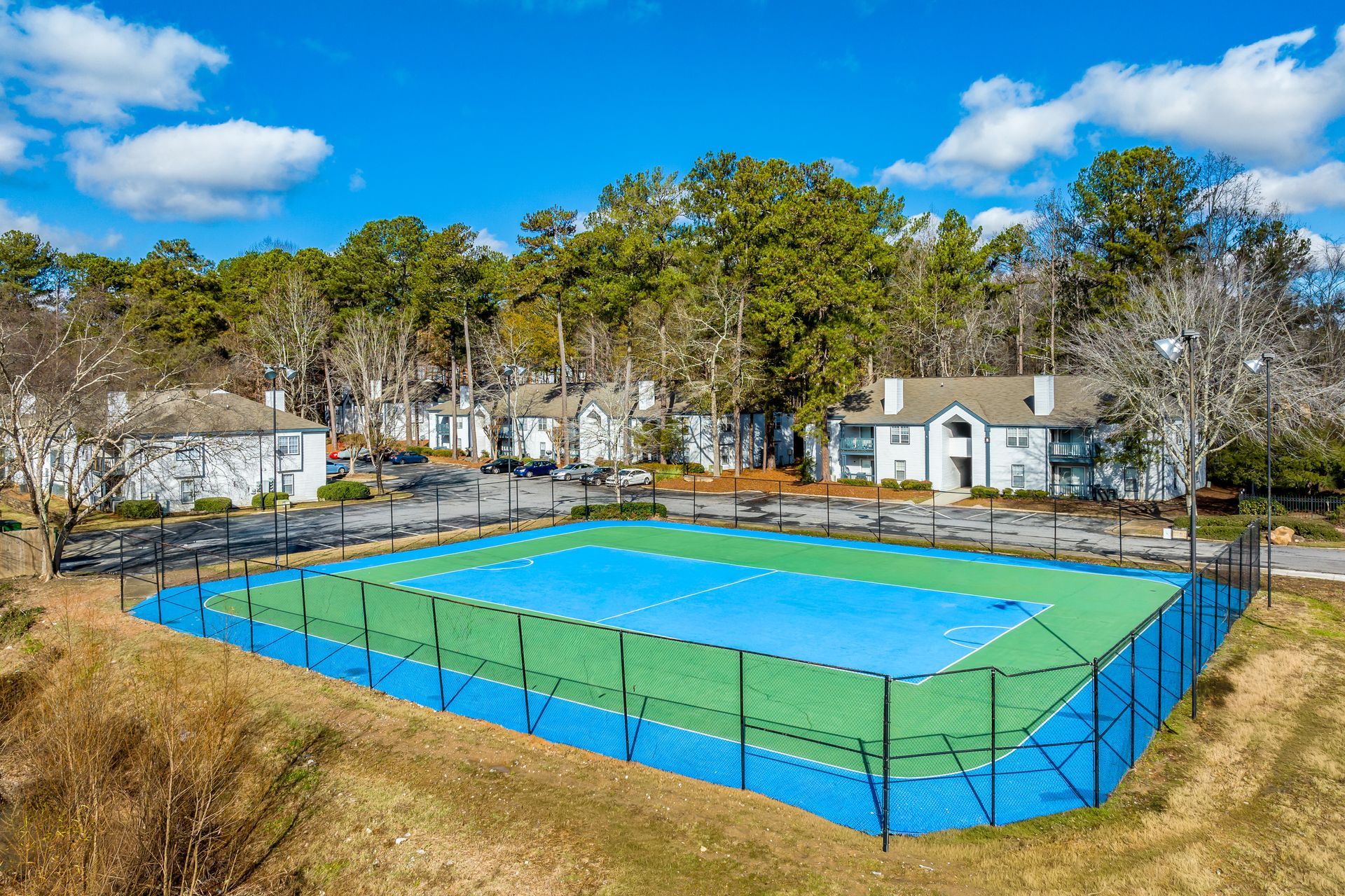 Ranch-style house with brick and gray exterior, pillars, surrounded by greenery and lawn.