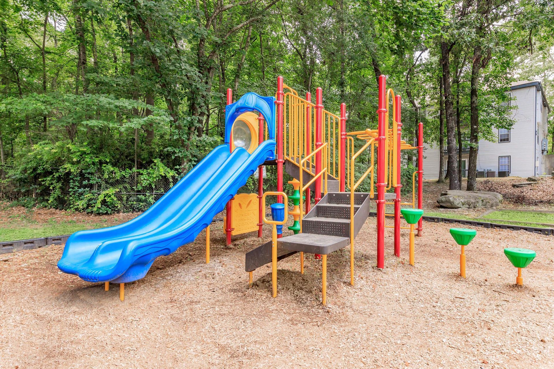Swimming pool with lounge chairs and parasols, surrounded by trees and a building.