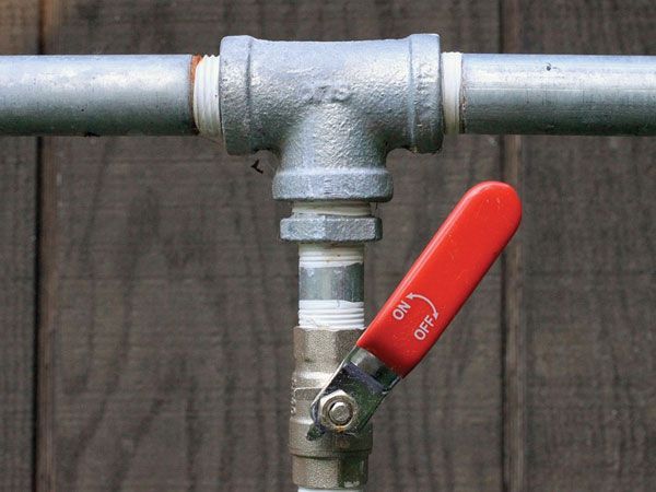 Galvanized pipes with a red-handled ball valve, showing ON and OFF positions.