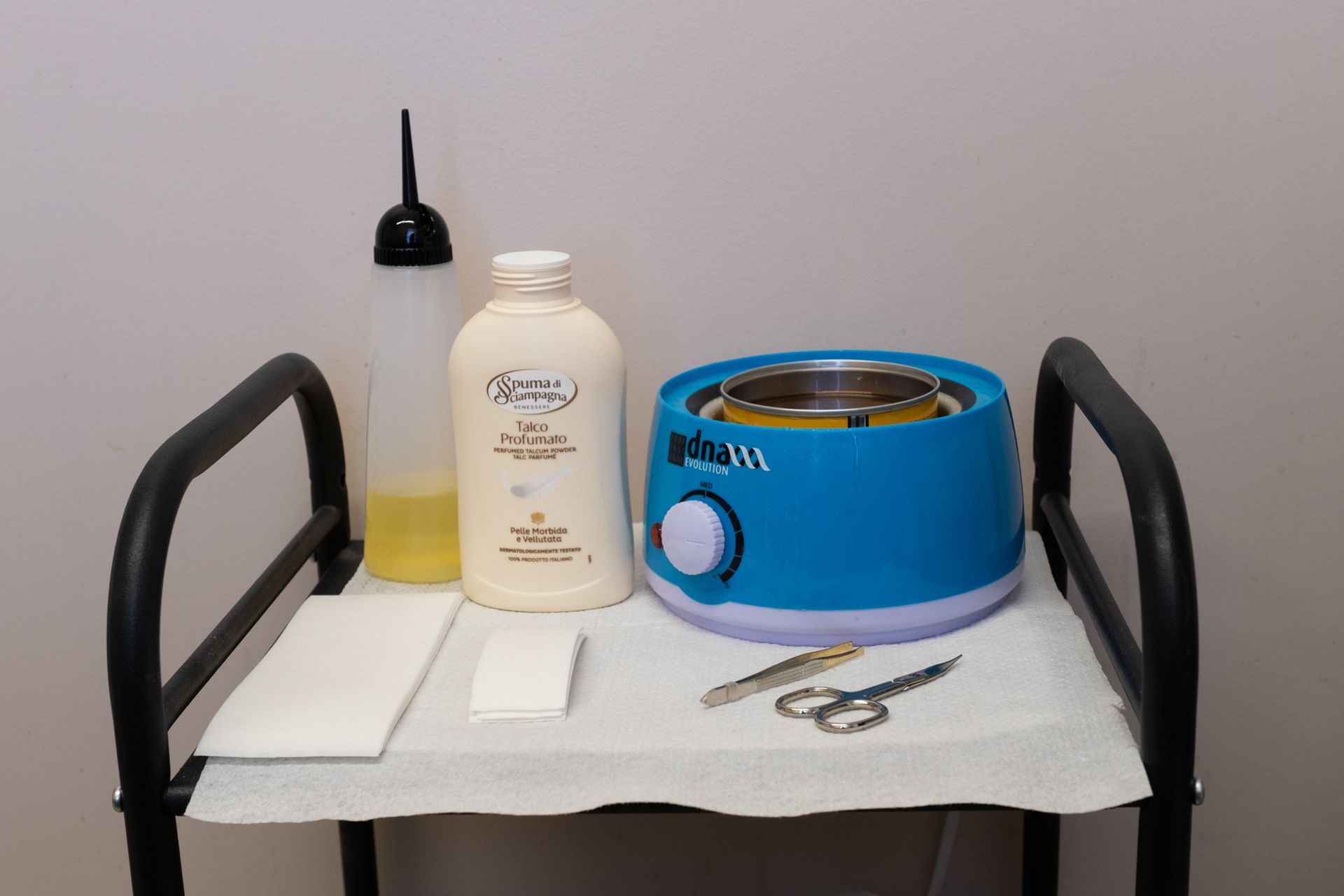 un carrello pieno di prodotti per la depilazione e una bottiglia di cera .