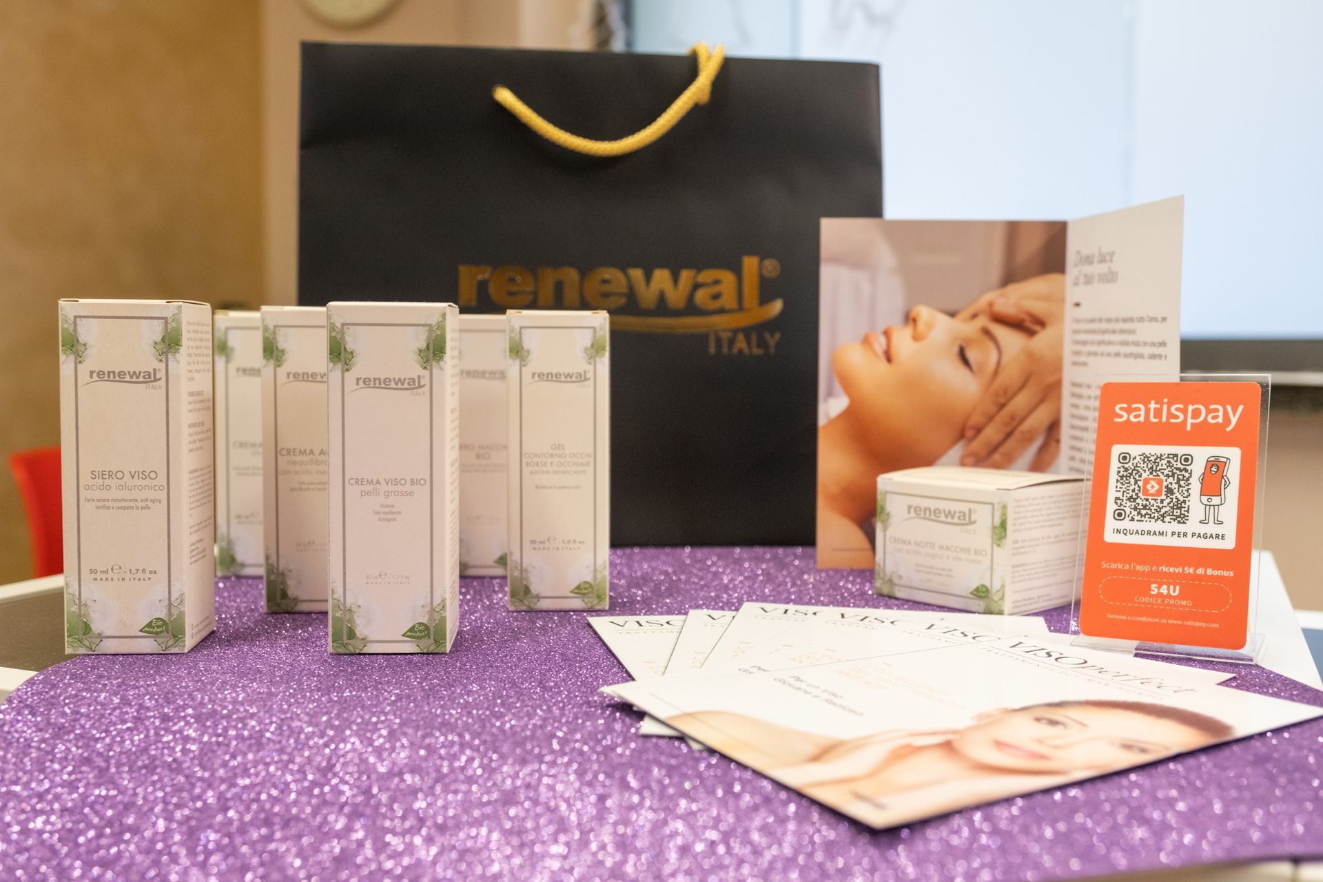 un tavolo pieno di prodotti per la cura della pelle e una borsa nera che dice renewal italy