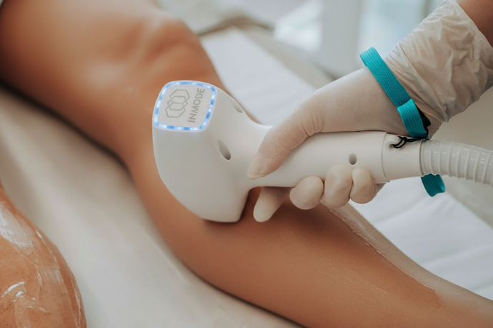 Epilazione laser su una gamba; una mano guantata aziona il dispositivo in un ambiente simile a quello di una spa.