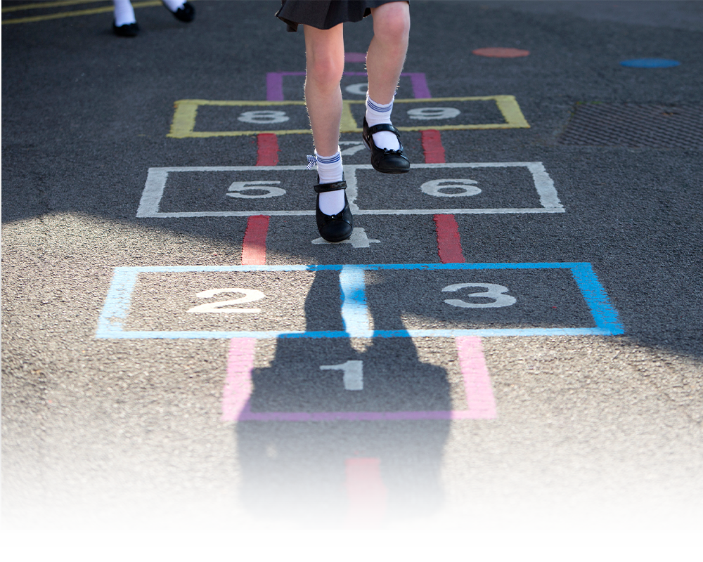 A girl is playing hopscotch on the sidewalk