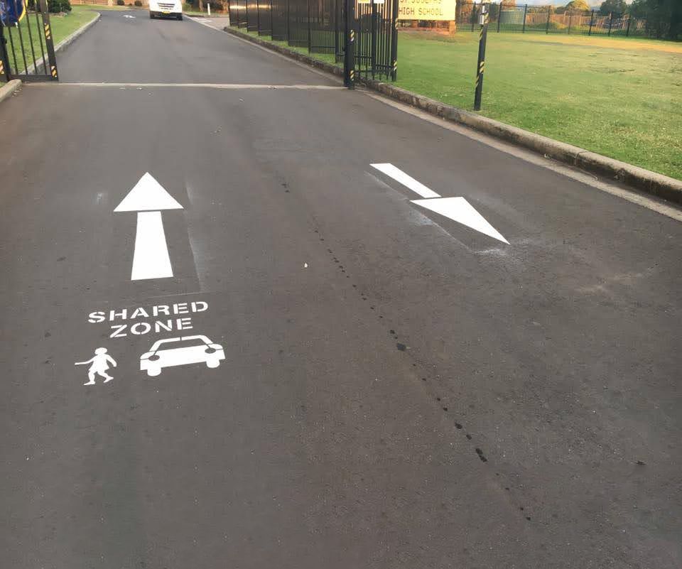 A shared zone sign is painted on the side of a road