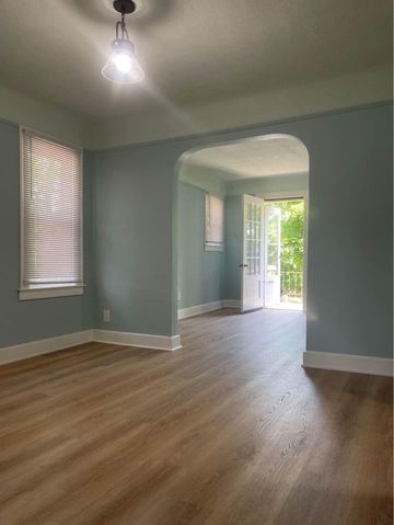 An empty living room with hardwood floors and blue walls.