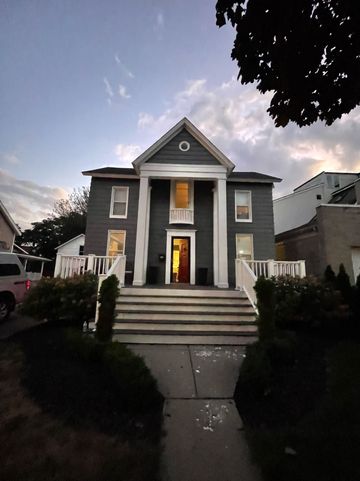 A large gray house with white columns and stairs