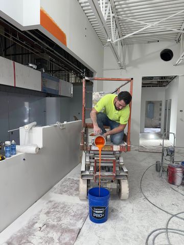 A man is sitting on a lift painting a wall.