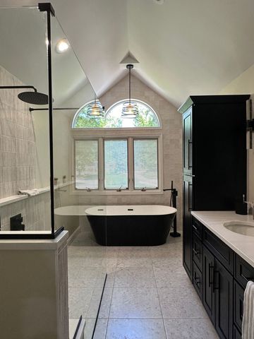A bathroom with a tub , sink , and shower.