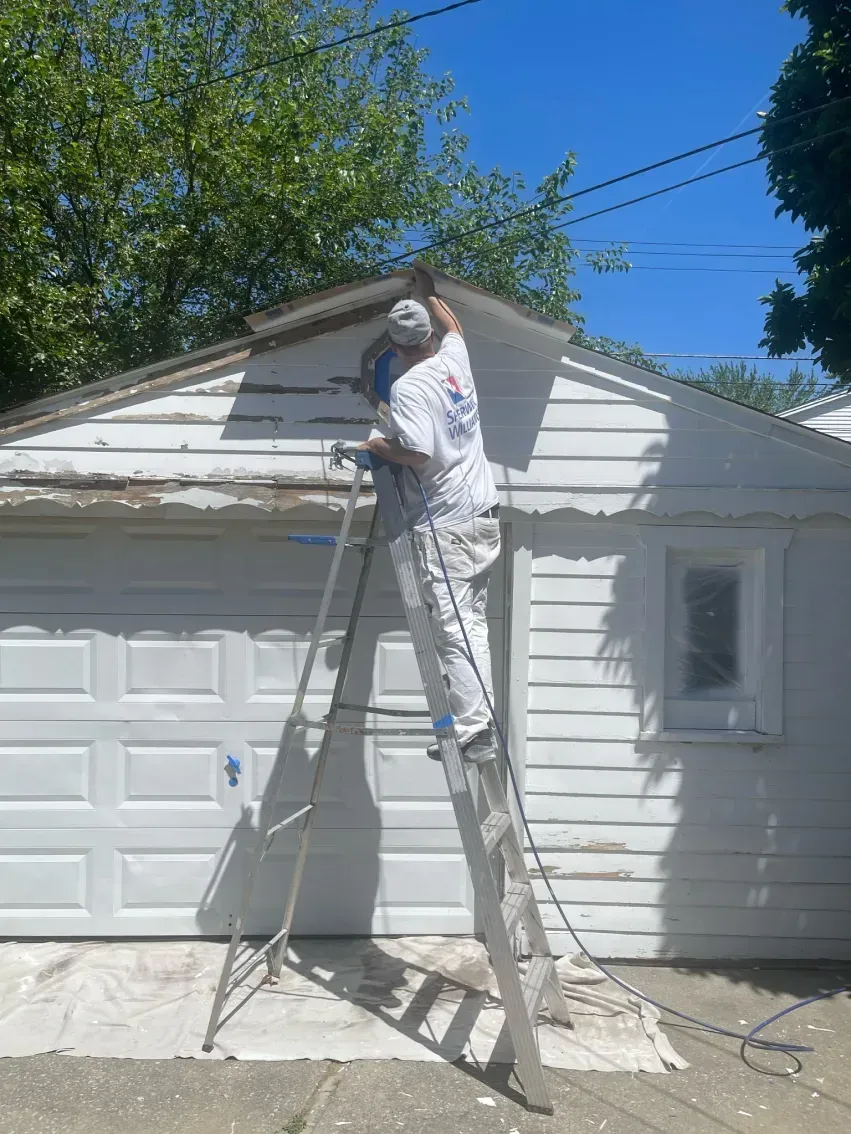 A man is standing in front of a green house.