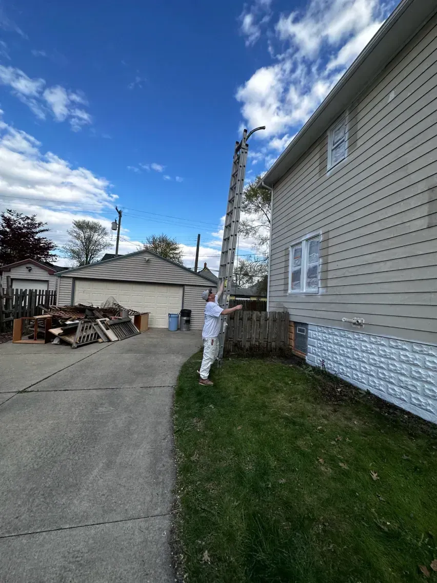 tall ladder against a house, reaching towards the roof. Sunny day, residential setting.