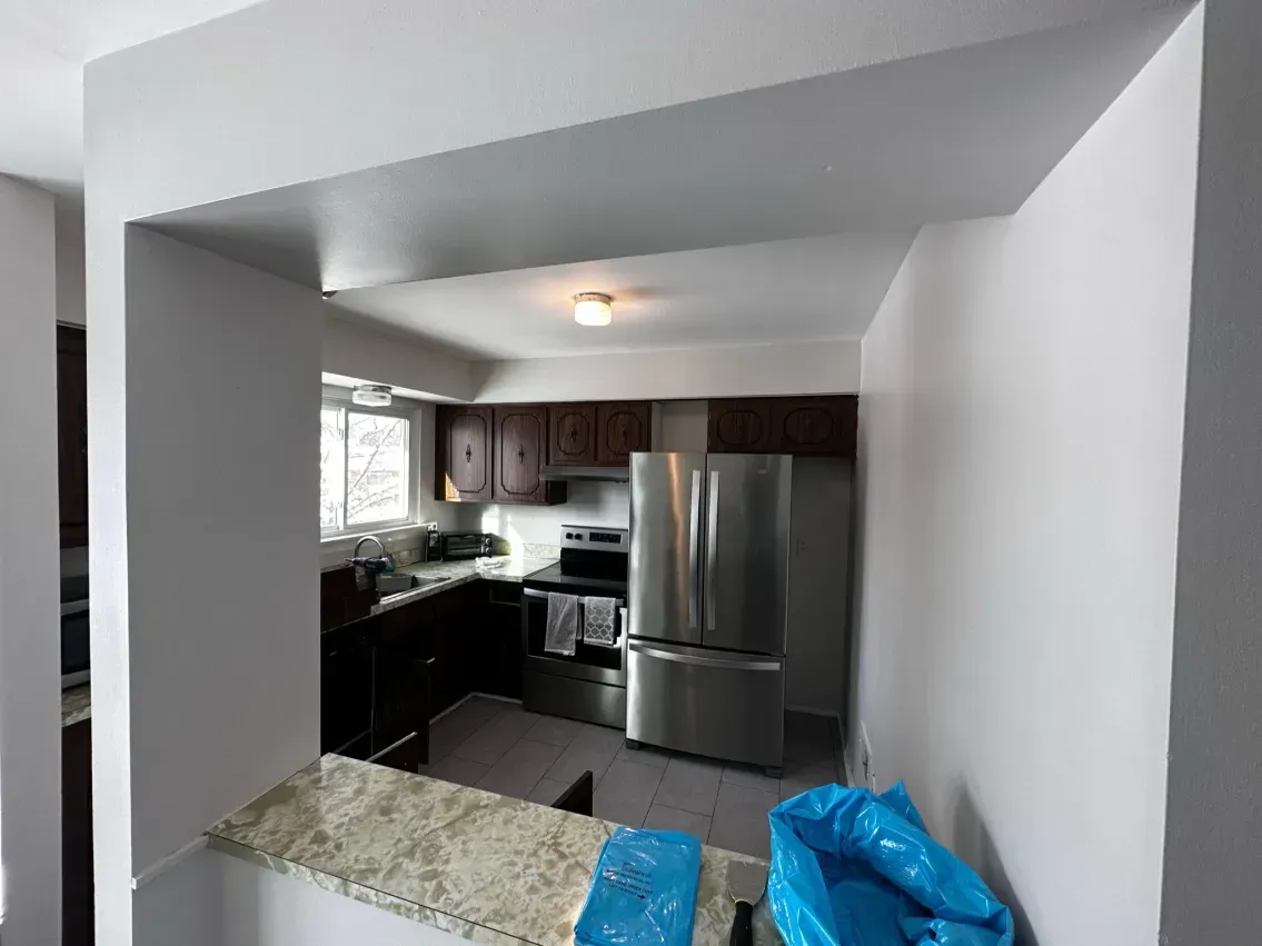partial granite countertop. Kitchen with stainless steel appliances is visible in the background.