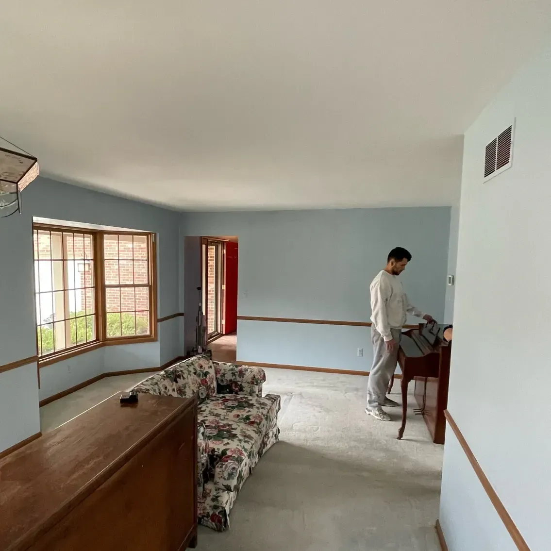 Living room with blue walls, a man, and floral couch.