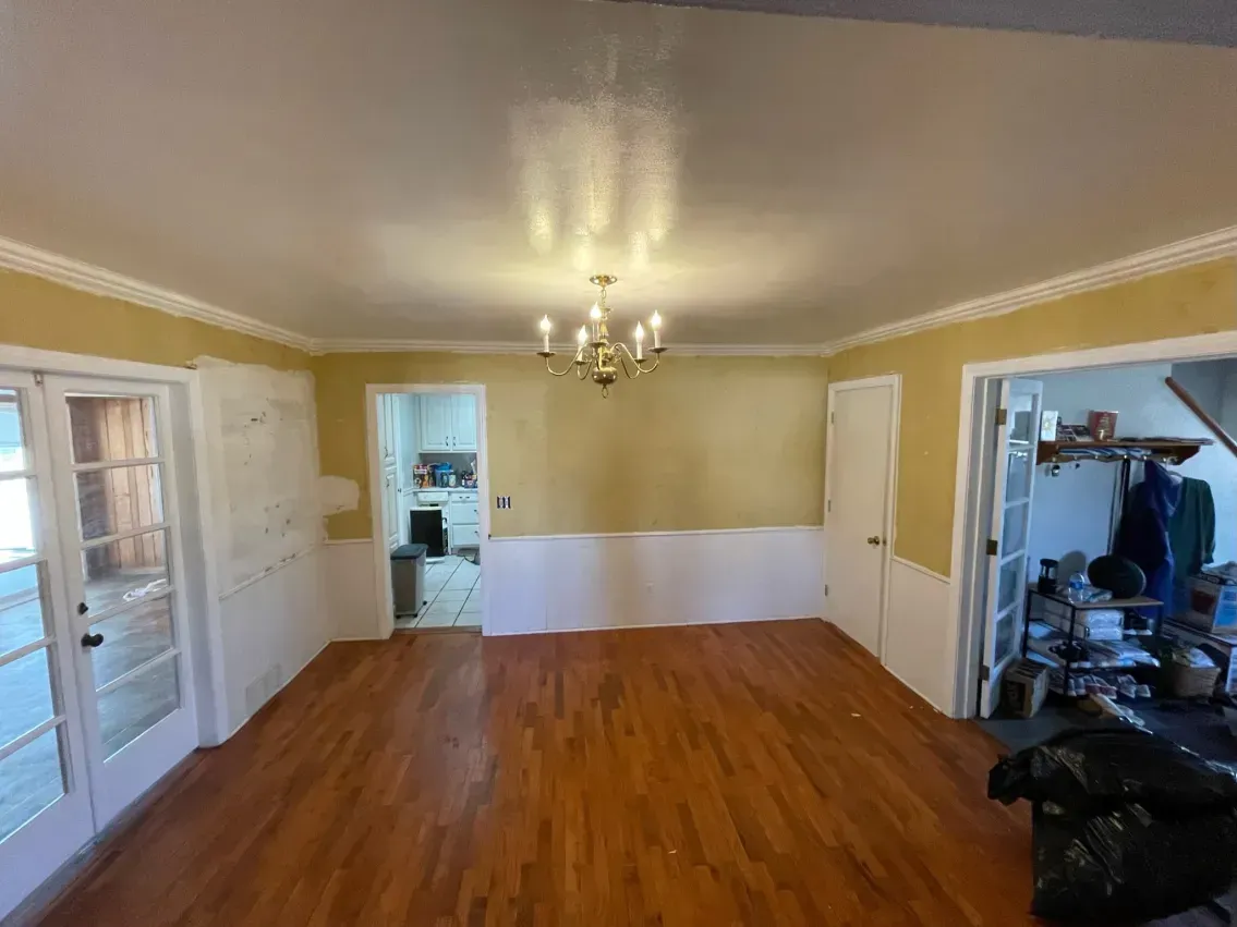 Empty dining room with wood floor, white and yellow walls, and chandelier.
