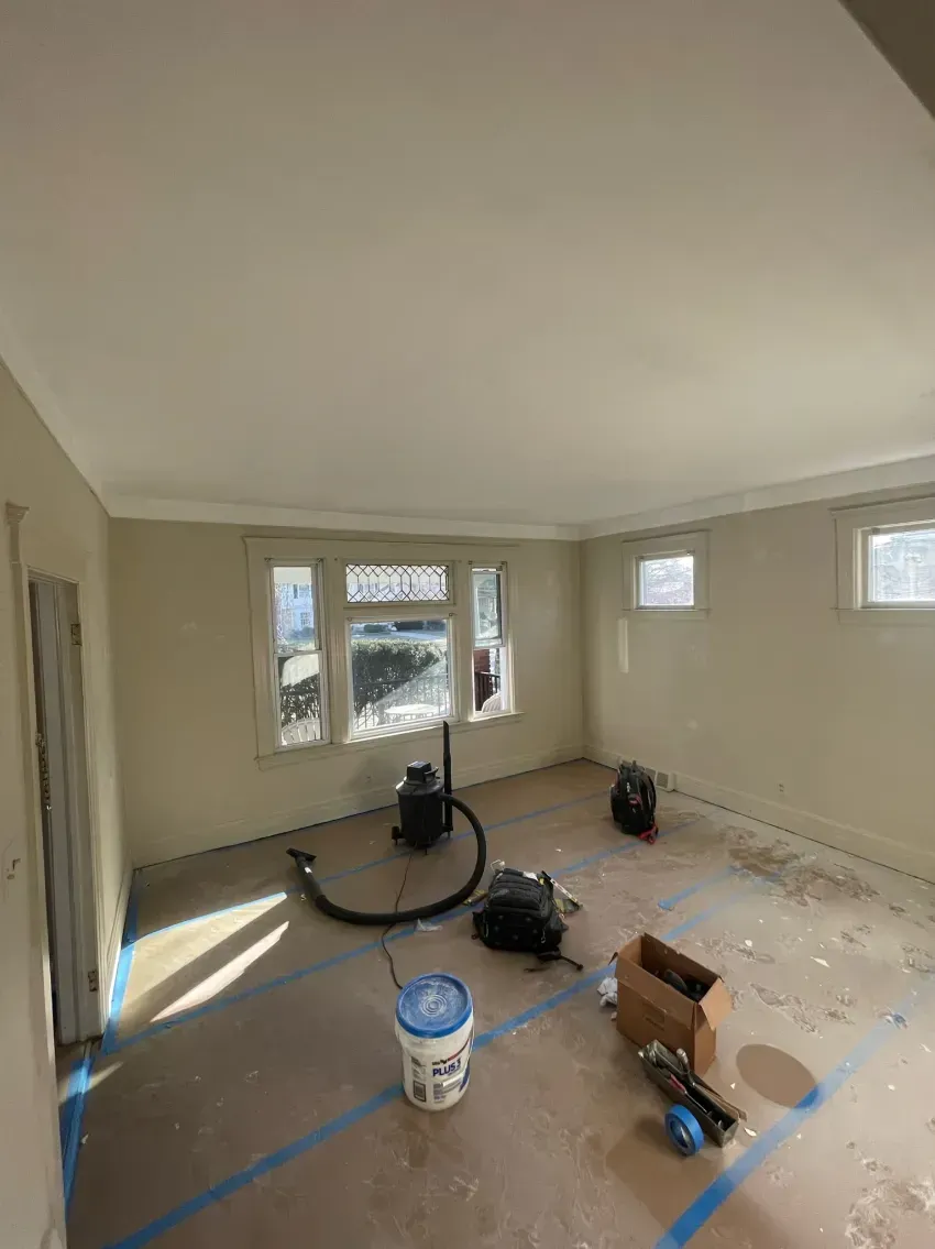 Room under renovation with painted walls and ceiling, taped floor, and equipment.