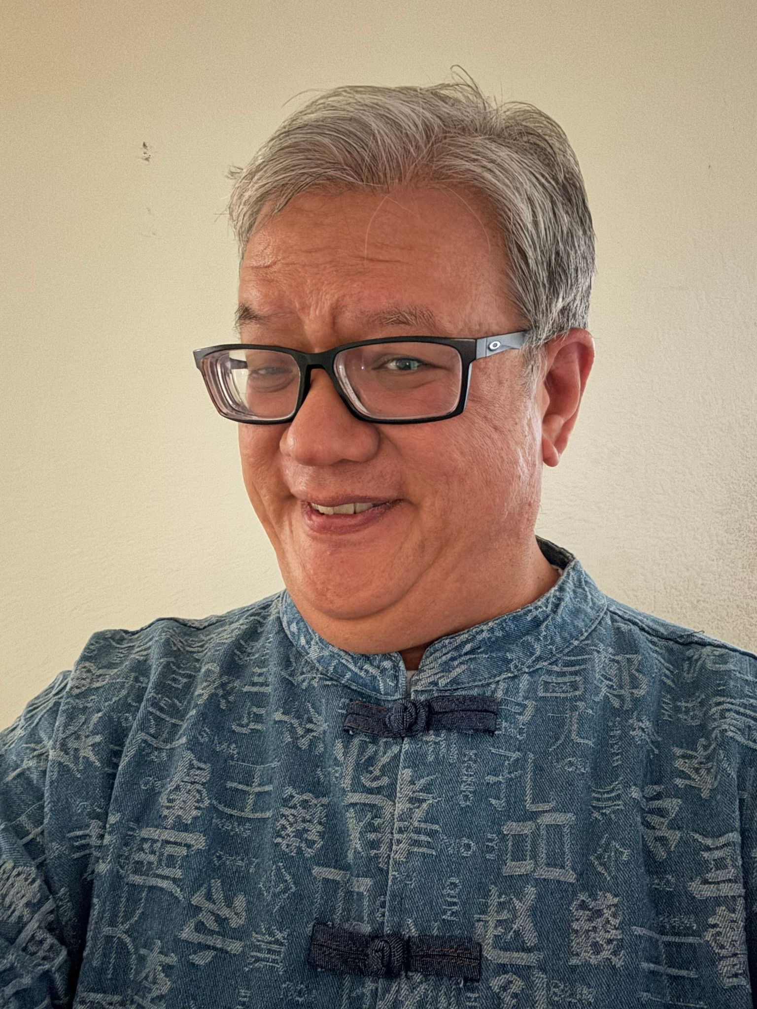 Man with glasses smiling; graying hair; close-up.