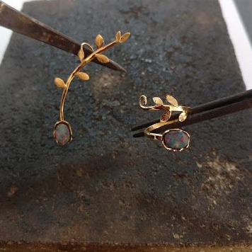 Um par de brincos e um anel estão sendo feitos sobre uma mesa.