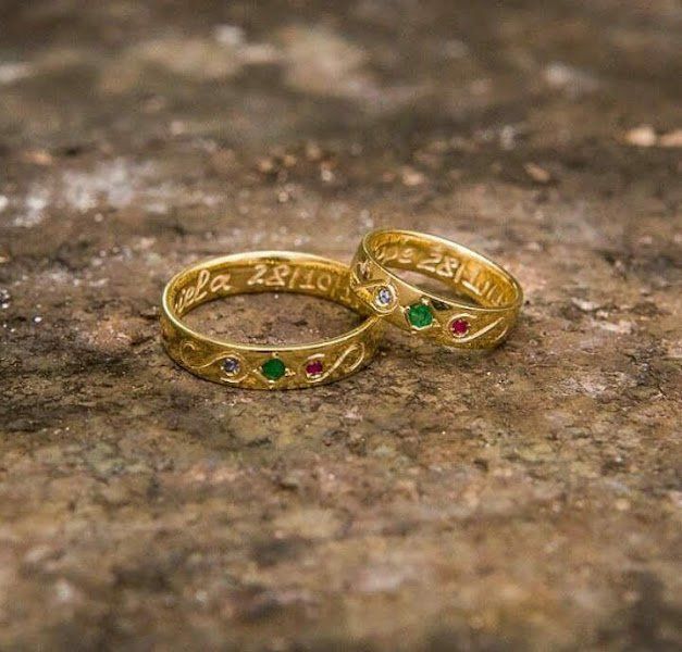 Um par de alianças de ouro em cima de uma pedra.