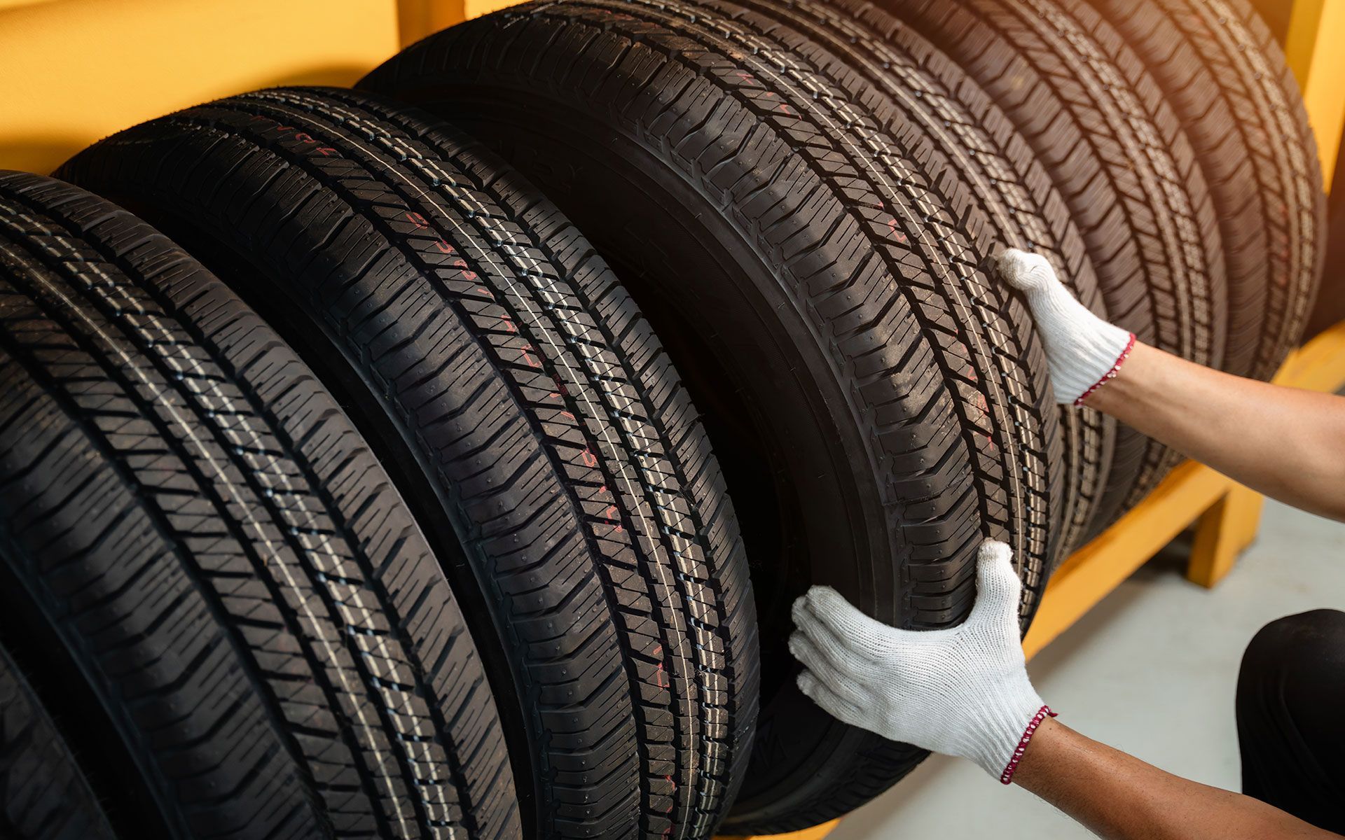 A person is holding a tire in front of a stack of tires.
