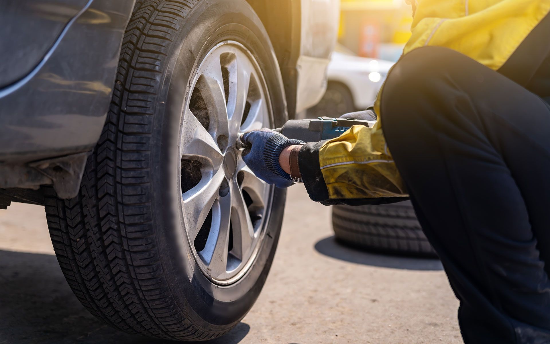 A man is changing a tire on a car with a wrench.