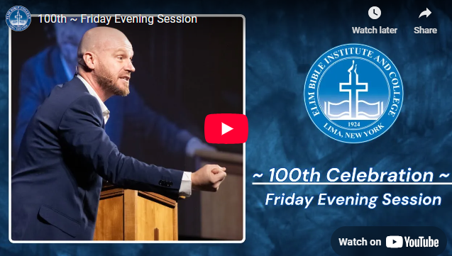 Man in a suit giving a speech at a podium during the 100th-anniversary celebration of a Bible institute in New York.
