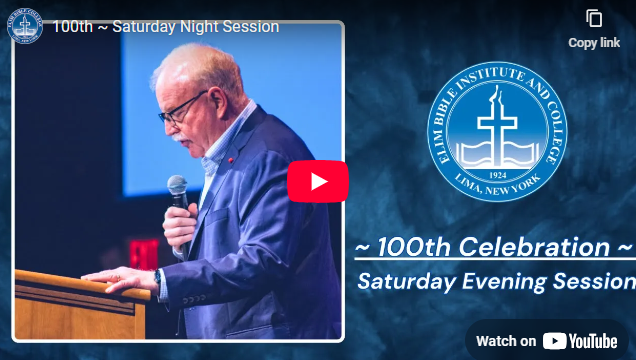 A man speaking at a lectern during a Saturday evening celebration at Elim Bible Institute & College.