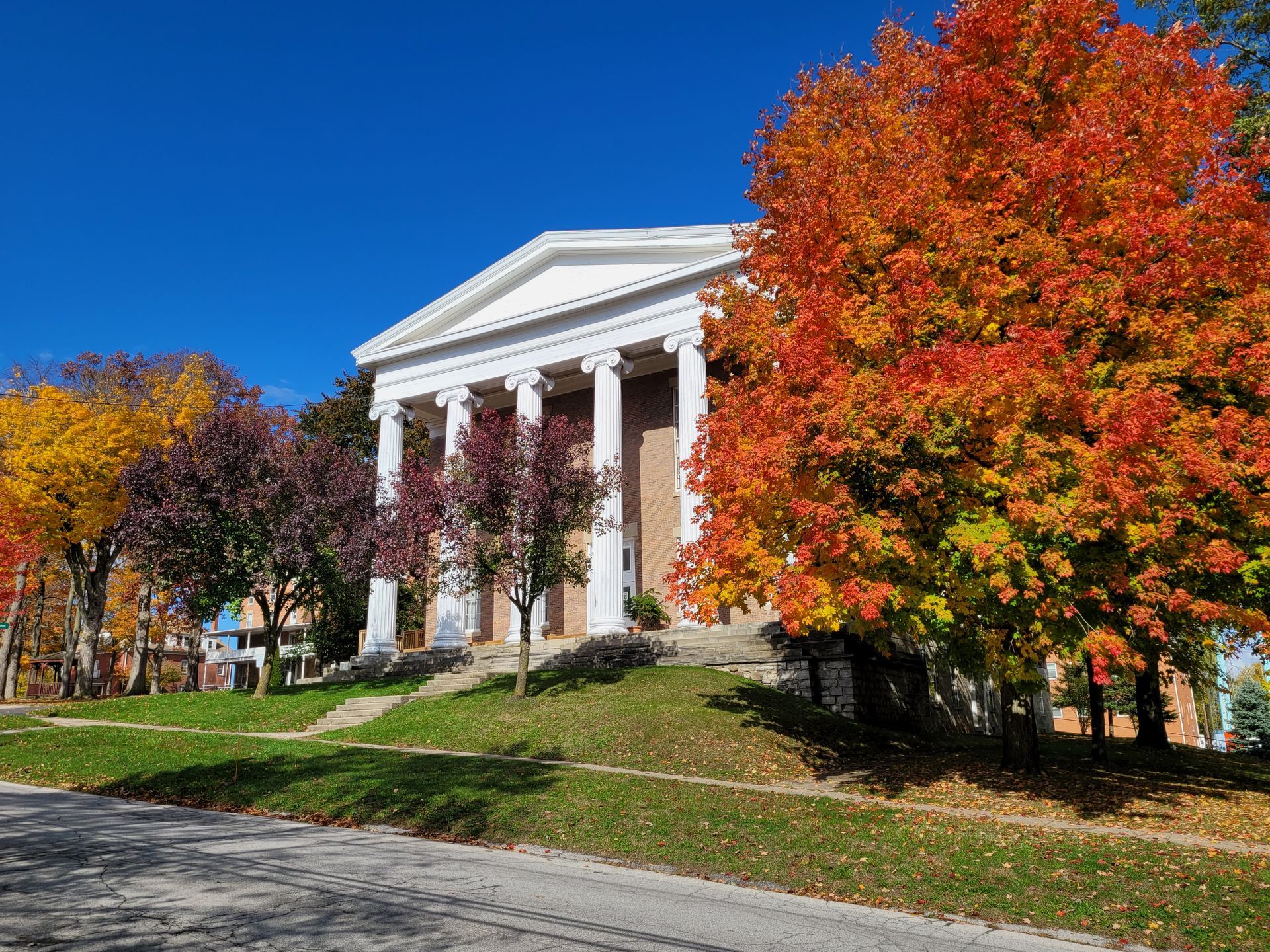 College Hall, a large brick building fronted by six white columns, surrounded by fall foliage.
