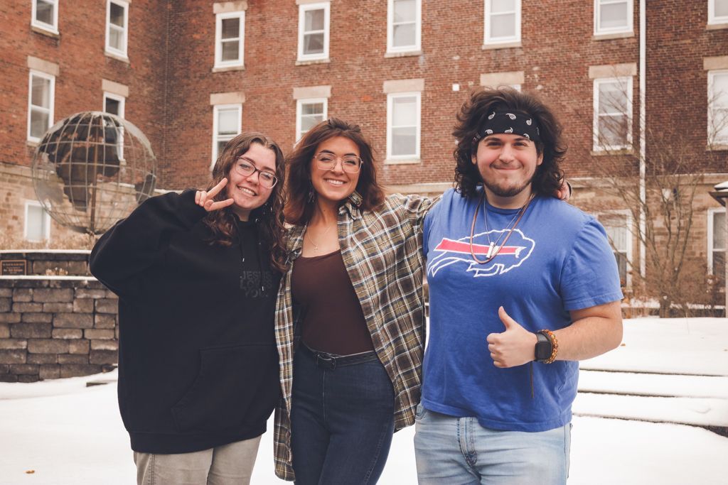 Three students smile for a picture outside