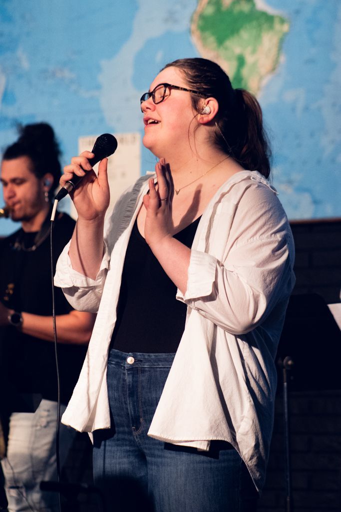 a student singing on stage during a chapel service