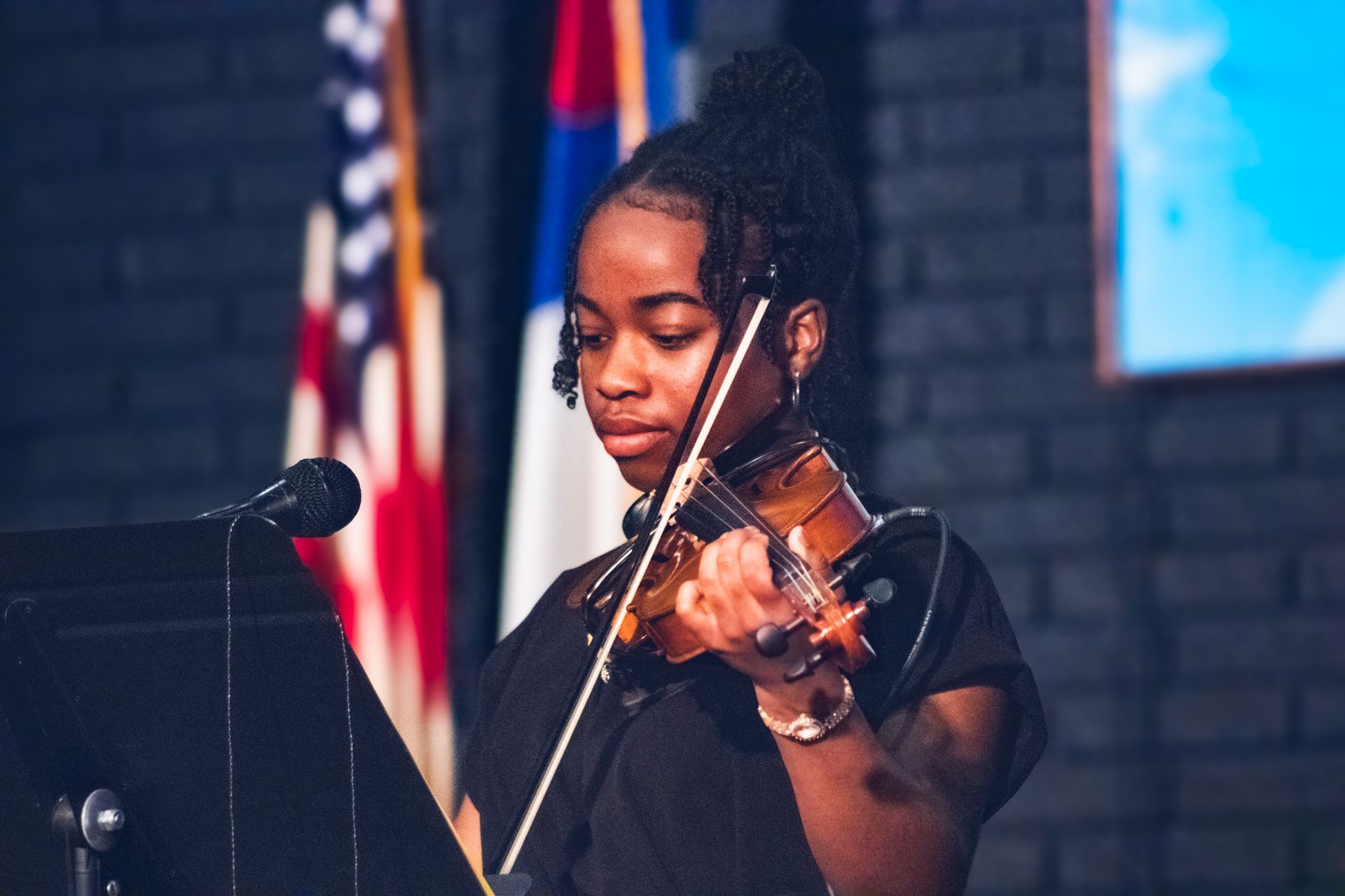 A female student playing violin on stage during chapel.