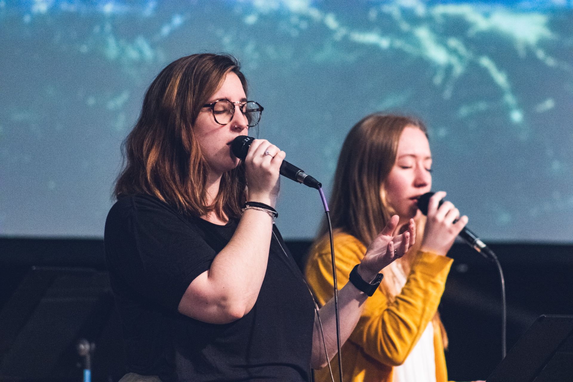 Two women are singing and leading worship