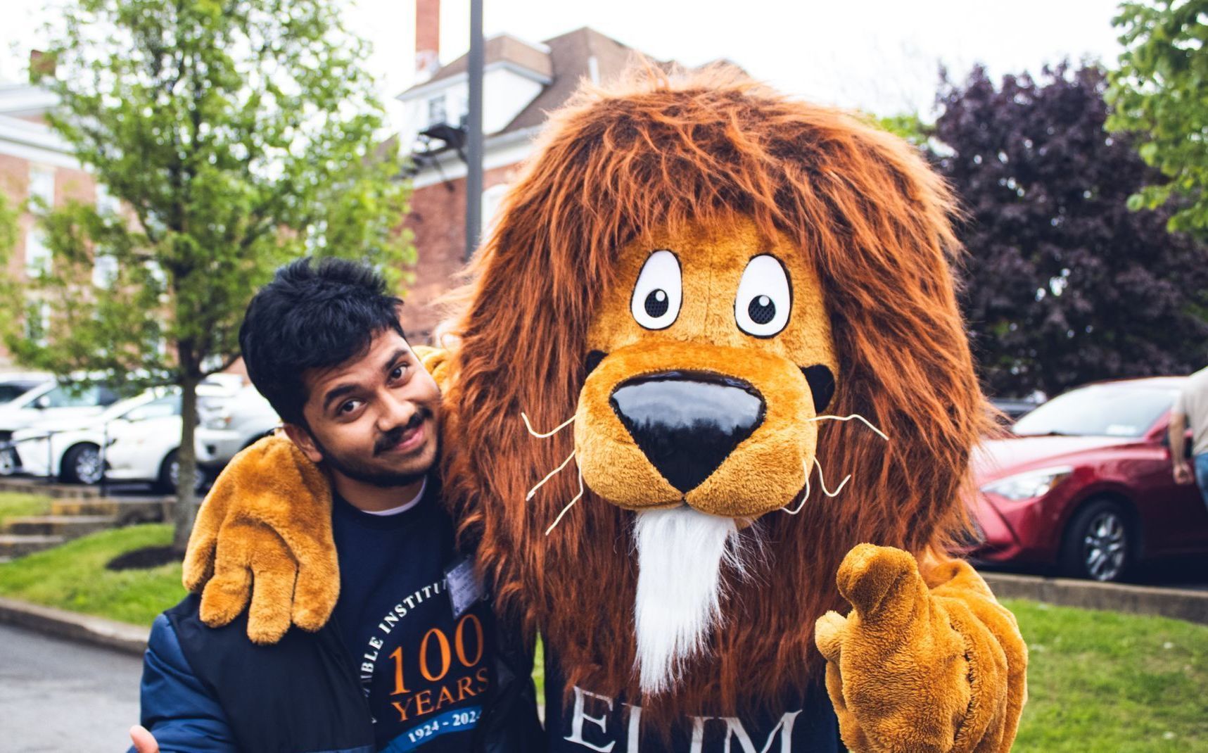 a student standing outside with the Judah the lion mascot